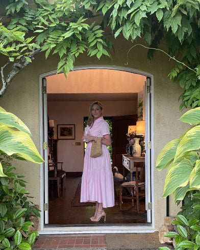 Woman in a pink dress standing in an open doorway surrounded by greenery